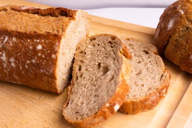 sliced whole grain bread on a wooden cutting board - on a white background