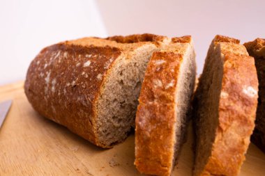 close-up of bread which is sliced on a wooden cutting board - on a white background