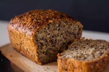 bread with different seeds sliced on a wooden cutting board - on a white table with a dark background