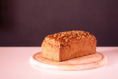 rye bread on a round wooden cutting board sprinkled with sunflower seeds - on a white table on a gray background