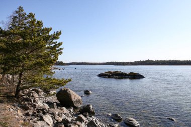 Uçurum yolu metal bariyer manzaralı bir sürü kaya ve açık mavi gökyüzü.