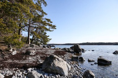 Uçurum yolu metal bariyer manzaralı bir sürü kaya ve açık mavi gökyüzü.