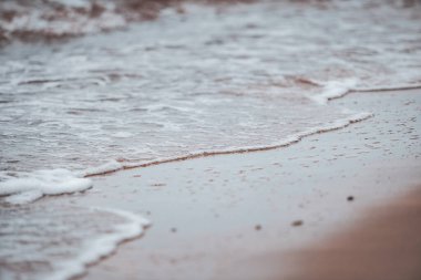Kum ve küçük dalgalarla Baltık kıyısı manzarası. Fotoğraf bulutlu, İskandinavya tarzı bir günde çekildi. Fotoğraf Letonya, Jurkalne 'de çekildi..