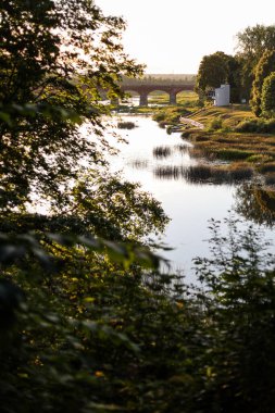 Venta nehri üzerinde eski kırmızı tuğlalı bir köprü olan ağaç manzarası. Fotoğraf Kuldiga 'da çekildi.