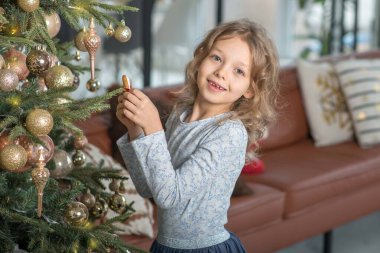 A happy little smiling girl with a Christmas tree and gingerbread horse.