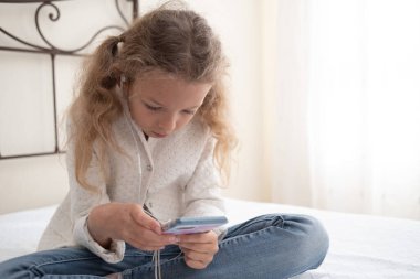 Child listening to music in headphones in bed room. High quality photo