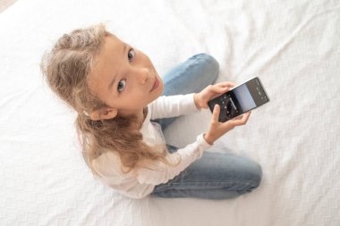 Child listening to music in headphones in bed room. High quality photo
