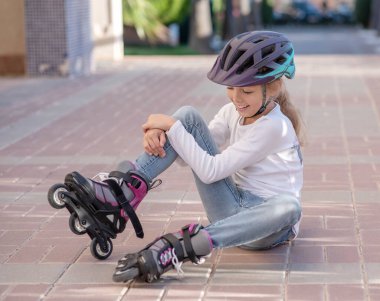 Kid stand with bottle of water, Child helmet for rollers, pretty little girl learning to roller skate outdoors, Happy girl, Have a free time. High quality photo