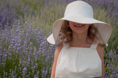 Girl in lavender field has white hat. Girl in white dress with a bouquet of lavender. High quality photo