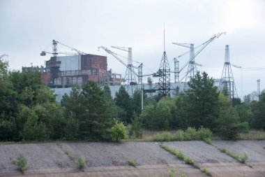 Pripyat şehri, Kiev bölgesi, Ukrayna - 2021: Çernobil nükleer santralinin acil durum dördüncü güç ünitesinde metal hangar barınağı ve Çernobil felaketinin kurbanları için bir anıt. Yüksek