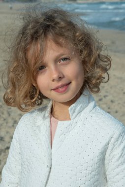 Kumsalda duran beyaz ceketli, gülümseyen kız. Yüksek kalite fotoğraf