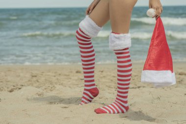 Legs child girl wearing Santa Claus socks on beach near sea, legs and skirt. Xmas vacation High quality photo clipart