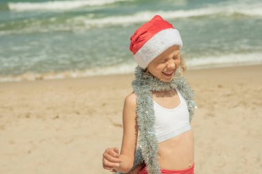 Plajda deniz kenarında Noel Baba şapkası takan çocuk, yüzü büyük. Xmas tatili Yüksek kaliteli fotoğraf