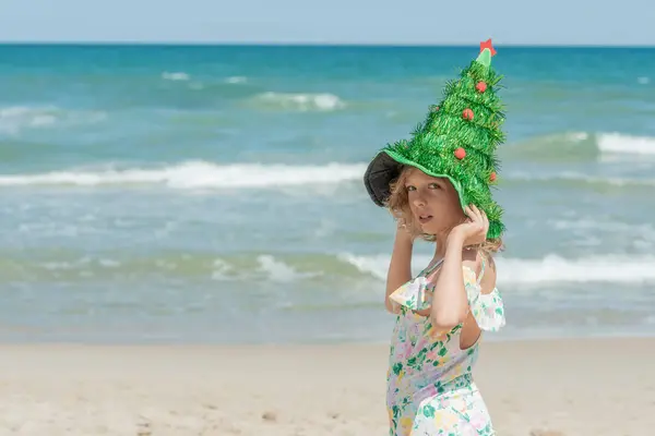 Deniz kenarında Noel ağacı şapkası takan bir kız çocuğu. Xmas tatili Yüksek kaliteli fotoğraf