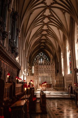 Yüksek kubbeli tavanları, süslü ahşap sıraları ve büyük bir vitray penceresi olan gotik bir katedral..