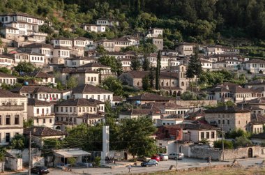 Arnavutluk 'un Berat kentindeki geleneksel Osmanlı tarzı beyaz taş evlerle çevrili, yemyeşil bir şehir. Binaların kahverengi kiremitli çatıları var. Uyumlu bir manzara yaratıyorlar. 