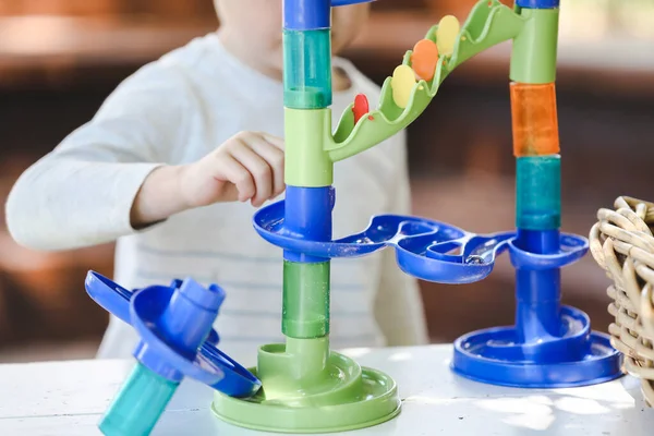 Child playing with colorful marble tower in preschool garden