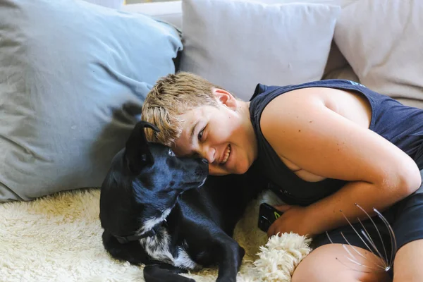 Мальчик Подросток Обнимается Диване Собакой Лучший Друг Человека Чёрная Порода — стоковое фото