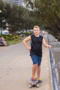 Çocuk, Queensland, Avustralya 'daki Altın Sahildeki Sörfçüler Cenneti' nde ana plaj geçidi boyunca kaykay yapıyor.