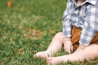 Yüzü olmayan bir bebeğin çimenlerde oturduğu görüntüsü.