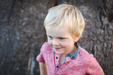 4 yaşında tatlı bir çocuk sakız ağacının önünde dikiliyor ve küstah bir ifade takınıyor.