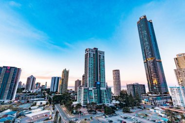 Sörfçüler Paradise QLD Avustralya - 9 Temmuz 2023: Yüksek binalar, apartmanlar ve günbatımında canlı renkli gökyüzü ile Gold Coast şehir siluetini oluşturan lüks oteller