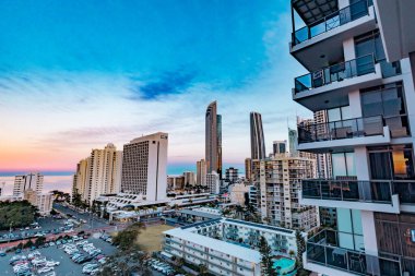 Sörfçüler Paradise QLD Avustralya - 9 Temmuz 2023: Yüksek binalar, apartmanlar ve günbatımında canlı renkli gökyüzü ile Gold Coast şehir siluetini oluşturan lüks oteller