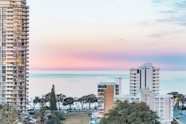 Sörfçüler Paradise QLD Avustralya - 9 Temmuz 2023: Yüksek binalar, apartmanlar ve günbatımında pembe ve mor gökyüzü ile Gold Coast 'a bakan lüks oteller
