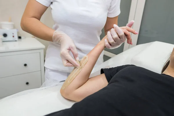 Sugar paste hair removal procedure - shugaring. Cosmetologist applies sugar paste to the hand of a young woman.