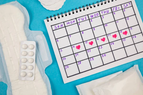 stock image Top view photo of sanitary pads, ladies calendar with marks on isolated blue background. The concept of women's periods.