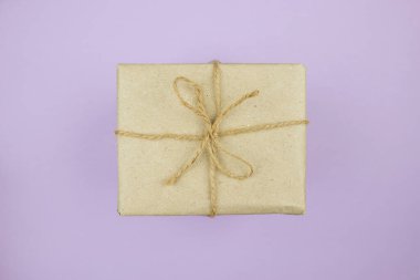 Mor arka planda kahverengi el işi kağıtları olan hediye kutusu. Üst manzara..