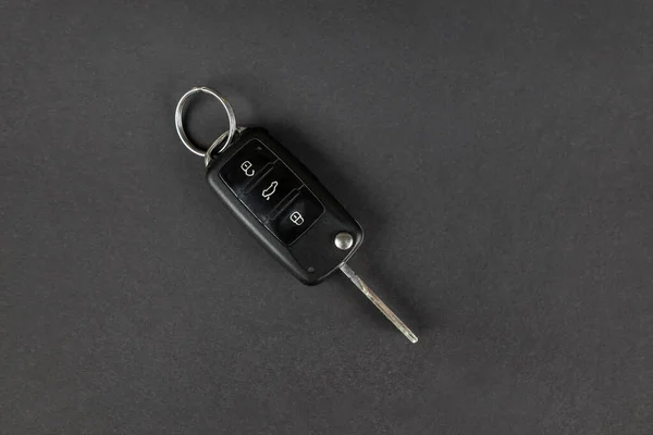 Modern car keys isolated on black background with copy space for text. Folding key with remote alarm and trunk release. View from above.
