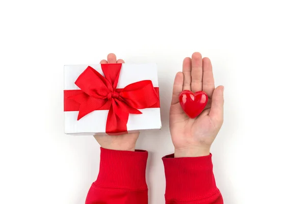 top view of valentines day decor, hands holding red heart and gift box with red ribbon bow on isolated white background