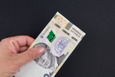 500 Hryvnia 'lı kadın siyah arka planda bir elde