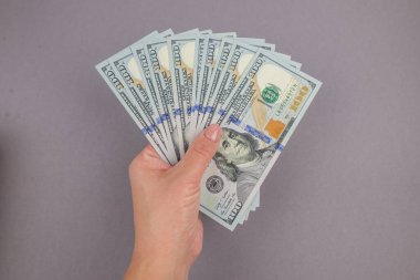 Gri bir arka planda bir kadın elinde dolar