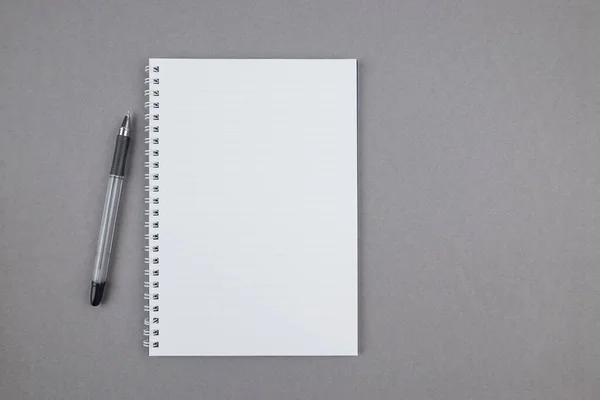 灰色の背景にペン付きの白いノートブックトップビュー 空のメモ帳 テキストのための場所 コピースペース — ストック写真