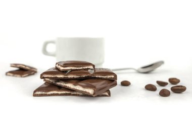 pieces of chocolate and a cup of coffee on a white background