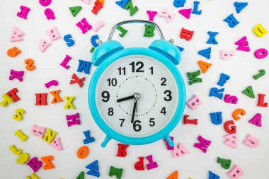 Top view of a blue alarm clock on colored letters. 8.30 am. It's time to go to school. lesson time.