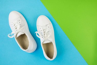 Mavi-yeşil zemin üzerinde beyaz ayakkabıların fotokopi alanı ile üst görünüm fotoğrafı.