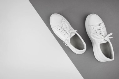 Gri ve beyaz arkaplandaki beyaz spor ayakkabılarının fotokopi alanı ile en üstteki görünümü.