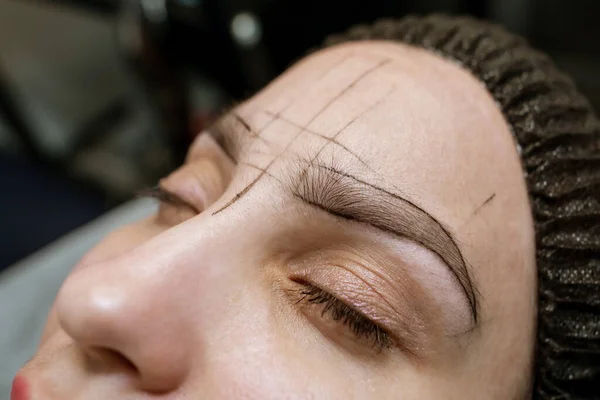 woman's eyebrows with guide lines around the eyebrows to get the exact measurements for the permanent eyebrow makeup procedure.