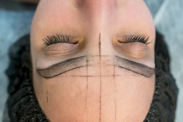 woman\'s eyebrows with guide lines around the eyebrows to get the exact measurements for the permanent eyebrow makeup procedure.