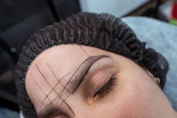 woman's eyebrows with guide lines around the eyebrows to get the exact measurements for the permanent eyebrow makeup procedure.