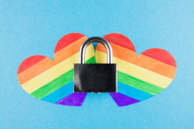 Igbt hakları kavramı, mavi arka planda asma kilit olan iki kalp, lgbt bayrağı gibi boyanmış kalpler.