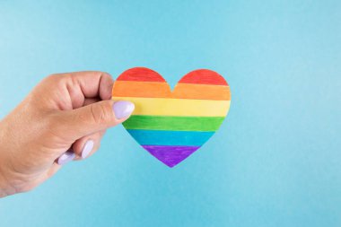 lgbt hakları kavramı, mavi arkaplanda el ele tutuşan bir kalp, lgbt bayrağı renginde, kopyalama alanı.