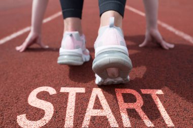 Rear view of a woman getting ready to start on the athletics track. beginning of New Year 2024, planning, goal and new year resolution. clipart