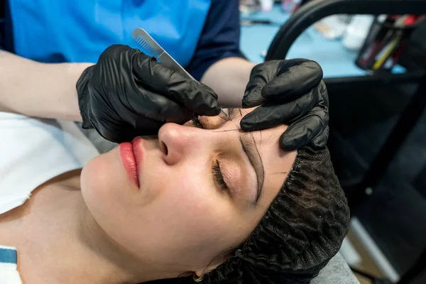 stock image Makeup artist plucks eyebrows in a beauty salon. Professional makeup and cosmetology skin care.