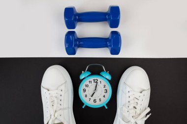 Beyaz saatli dambıl spor ayakkabıları ve diğer spor aletlerinin en üstteki fotoğrafı. Yoga fitness spor zayıflama konsepti