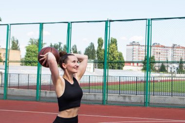 Atletik bayan basketbolcu topu ağlara atıyor..