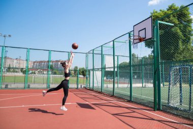 Atletik bayan basketbolcu topu ağlara atıyor..